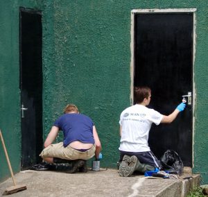 Volunteers painting the doors to the male sleeping chalet